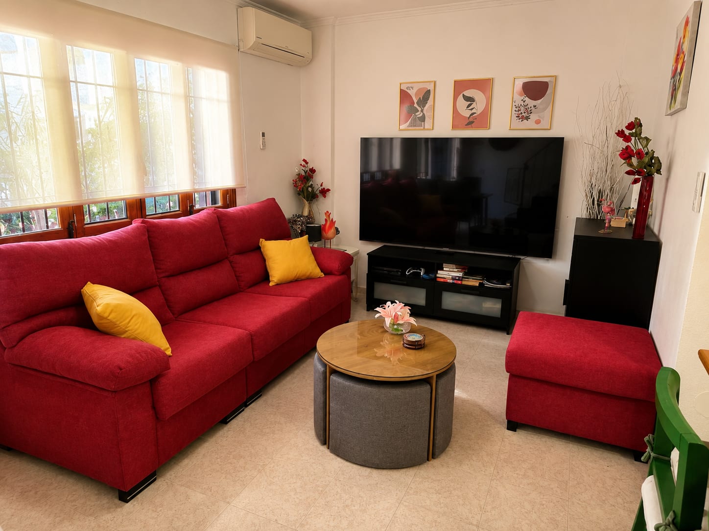 Sitzecke der Casa Flamingo mit rotem Sofa und Smart-TV